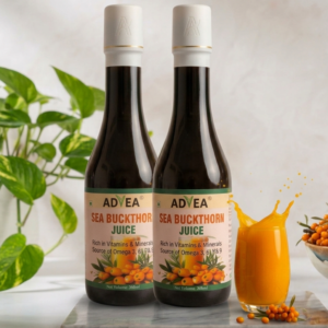 A premium product shot of an ADVEA Sea Buckthorn Juice dark glass bottle featuring an elegant matte white cap with a gold rim accent. The bottle stands on a white marble slab next to a splashing glass of vibrant orange juice, fresh sea buckthorn berries, and a potted green plant on a bright, modern kitchen counter backdrop.
